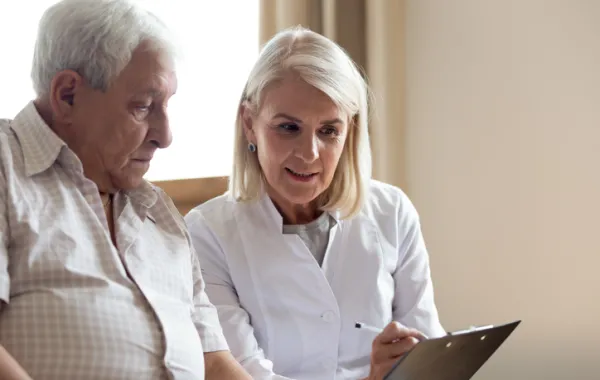 Foto de un señor mayor hablando con una trabajadora social