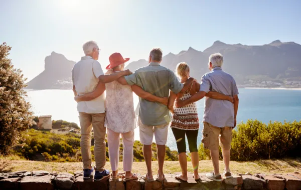 Foto de varias personas adultas en una montaña mirando el mar
