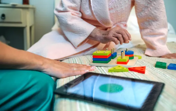 Foto de una persona mayor realizando un juego psicomotor con un especialista