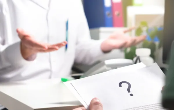 Foto de una manos que sostienen un papel con interrogación y otras que hacen el gesto de recibir