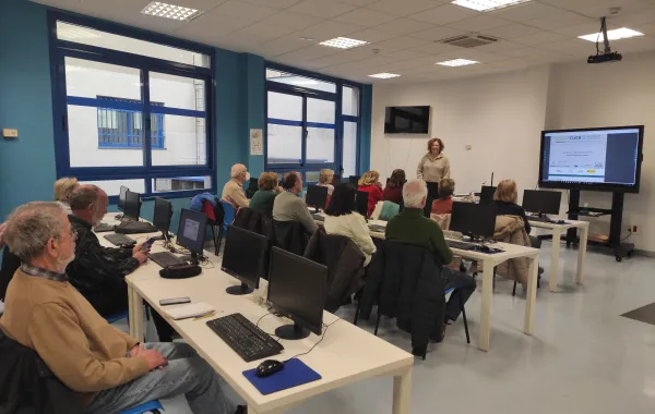 Foto de un aula de informatica con personas mayores aprendiendo