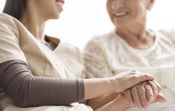 Foto de una mujer acompañada por una enfermera que le atiende y agarra la mano
