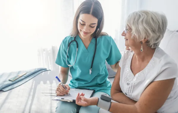 Foto de una mujer mayo atendida por una doctora que le midiendo la tensión