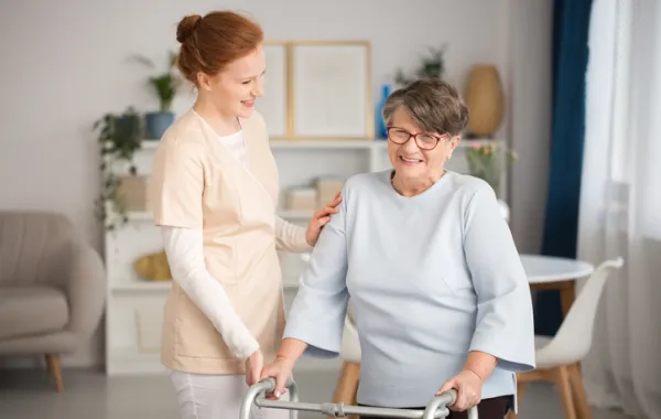 Foto de una mujer anciana acompañada por una enfermera