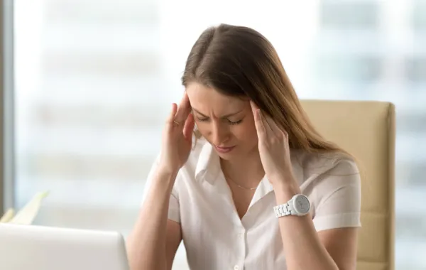 Foto mujer tocándose las sienes con gesto de dolor de cabeza