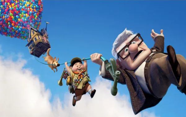 Foto película UP con el protagonista un anciano y un niño que se sujetan a una cuerda de globos que lleva la casa por los aires