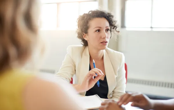 Foto de mujer seria en una reunión hablando e indicando importanciacon un gesto de la mano 