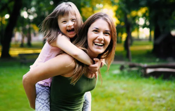 Foto de madre joven con su hija con síndrome de down sonriendo felices