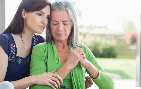 Foto de una mujer mayor con dolor acompañada de una mujer joven que la abraza