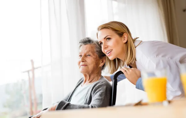 Foto de mujer mayor en silla de ruedas acompañada por una enfermera