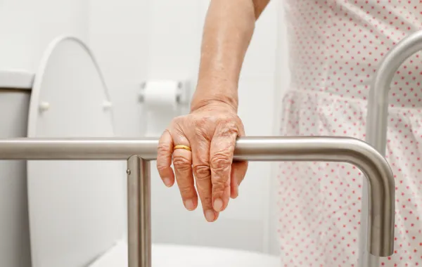 Foto de mano de mujer mayor agarrándose a una barra de sujección
