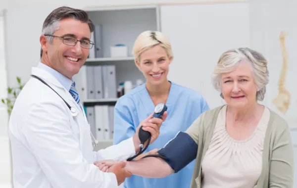 Foto mujer mayor que la toman la tensión un médico y una enfermera