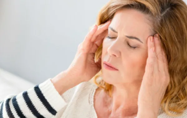 Foto mujer sentada con manos en las sienes y ojos cerrados