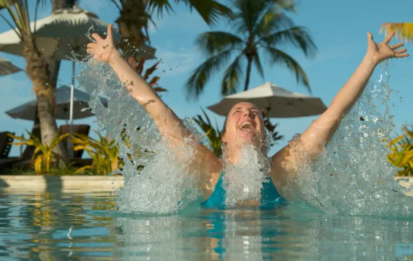 Foto de una mujer en la piscina que salta hacia arriba con los brazos abiertos