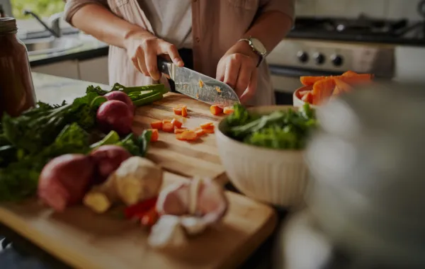 Foto de una persona cocinando y cortando verduras con un cuchillo