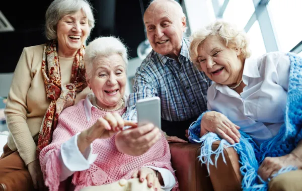 Foto de un grupo de personas mayores sonriendo mientras miran un movil