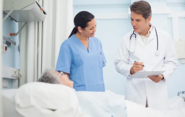 Foto de mujer mayor tumbada en una cama de hospital acompañada de medico y enfermera