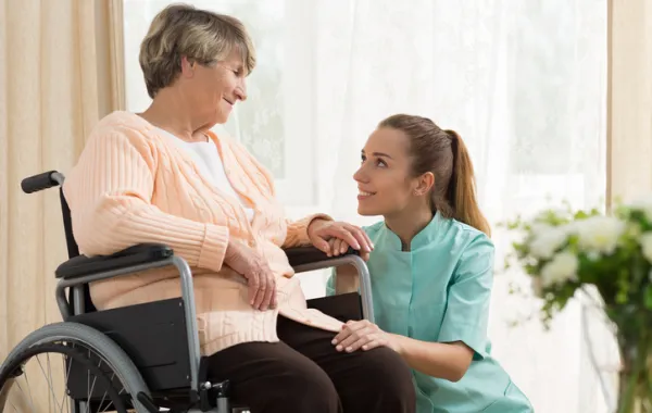 Foto de mujer mayor en silla de ruedas acompañada de una enfermera