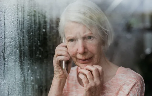 Foto de anciana con mirada triste y llamando por teléfono