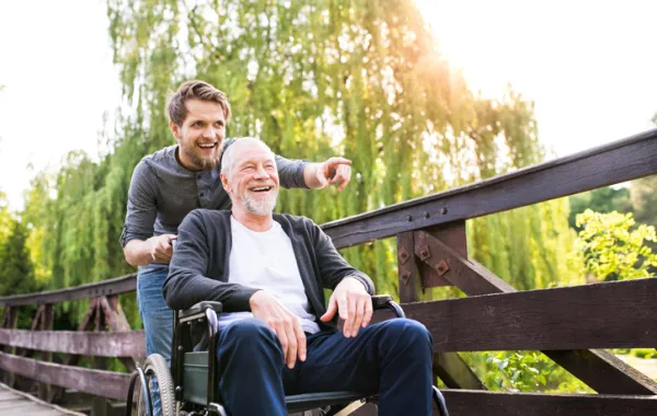 Señor mayor en silla de ruedas acompañado de un joven