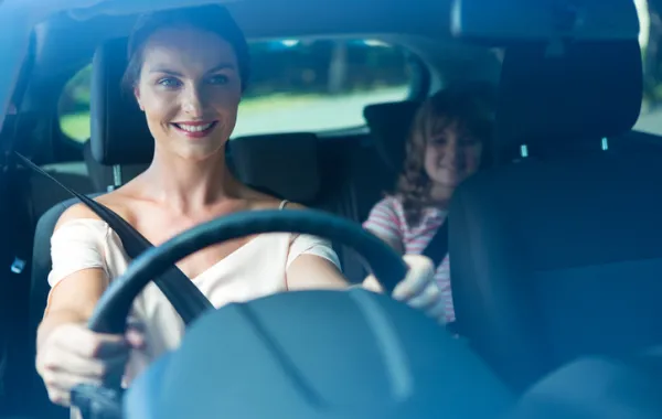 Foto de mujer conduciendo con cinturón y con silla con niño detrás