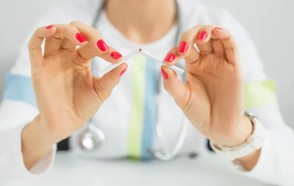 Foto de unas manos que rompen un cigarrillo por la mitad