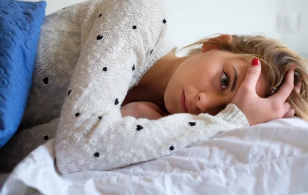 Foto de una adolescente tocándose la cabeza con la mano con gesto de dolor