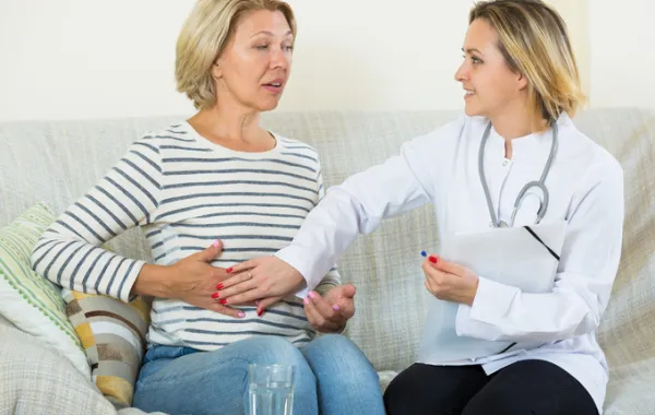 Foto de mujer con doctora de digestivo que palpa su vientre