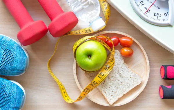 Foto con una manzana, tomates, báscula y elementos deportivos