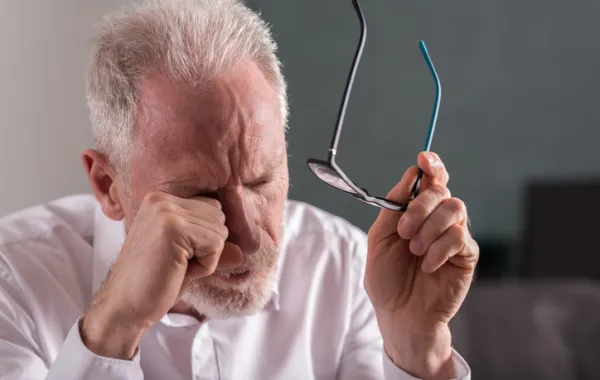 Foto de señor mayor con una mano en el ojo sintiendo dolor