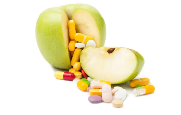 Foto de una manzana partida rodeadas de pastillas