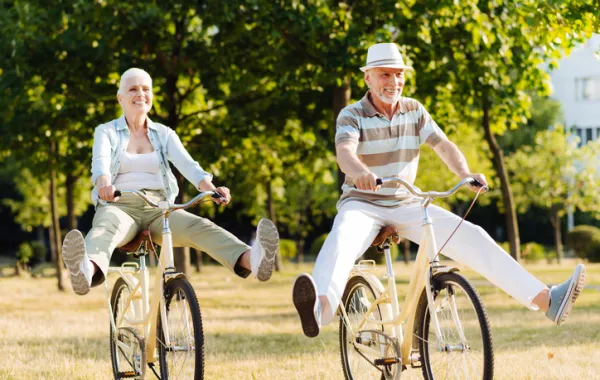 Foto de pareja de personas maduras montando en bici y sonriendo