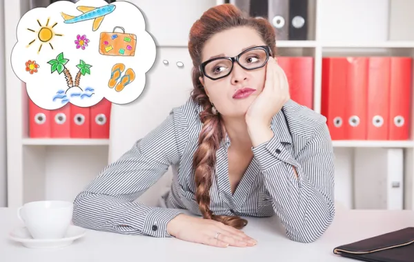 Foto de mujer en una oficina con cara de cansada y pensando en vacaciones