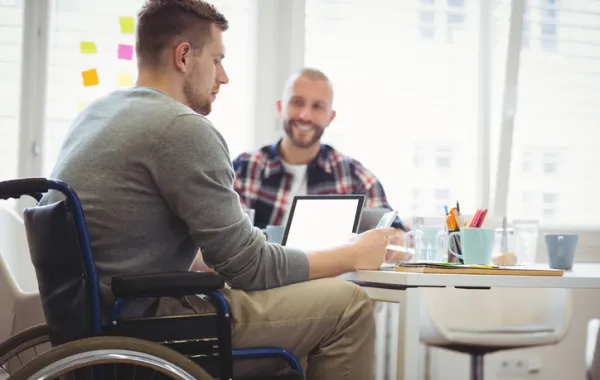 Foto de joven en sillas de ruedas hablando con otro joven
