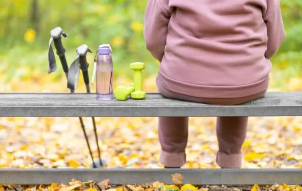 Persona sentada de espaldas en un banco de madera en un paraje natural
