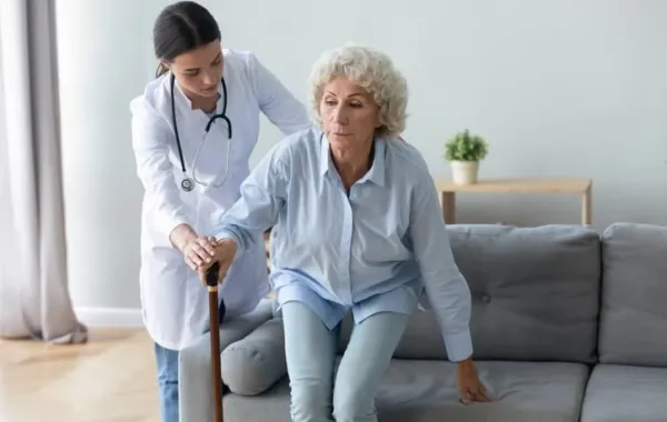 Una cuidadora ayudando a una paciente de Parkinson a incorporarse