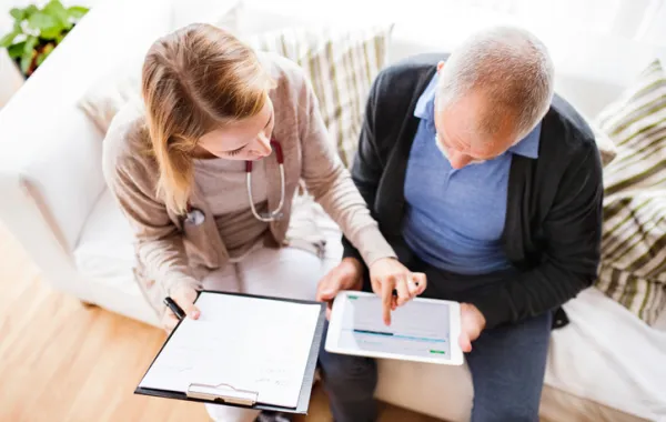 Foto de una mujer joven enseñando a un señor mayor un documento