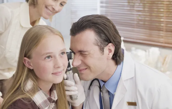 Foto de médico que observa el interior del oído de una niña