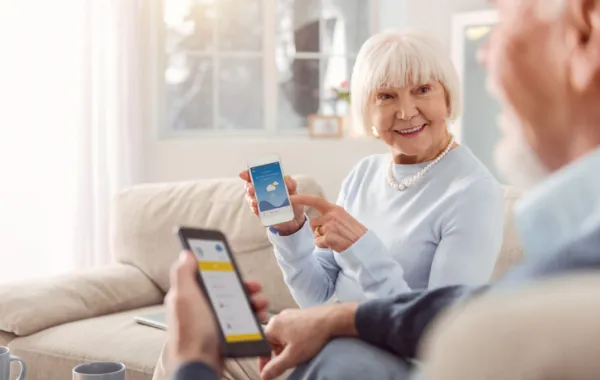 Foto de una pareja de personas mayores leyendo un texto en el movil y comentando
