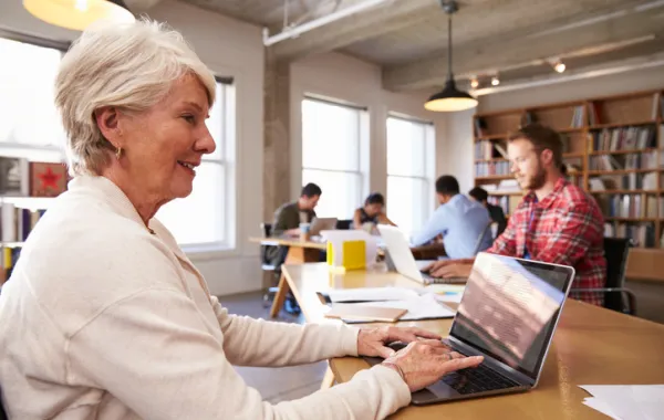 Foto de mujer mayor trabajando con un ordenador en una biblioteca