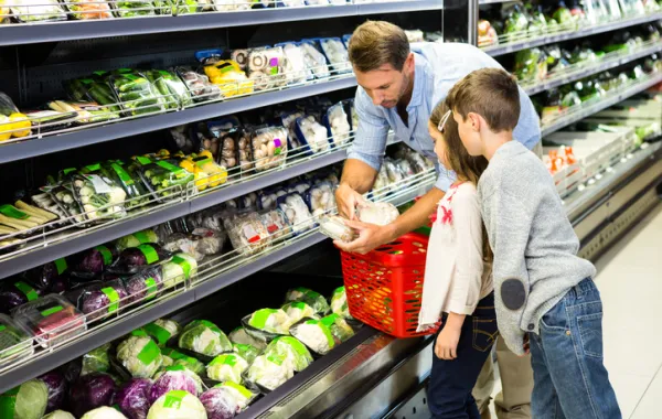 Foto de un padre comprando en el supermercado acompañado de sus hijos