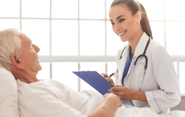 Foto mujer médico hablando con un paciente mayor tumbado en la cama y sonriendo
