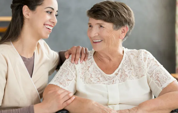Foto de mujer mayor acompañada de una mujer joven que sonríe