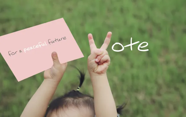 Foto de una mano de niño haciendo la señal de una V de votar