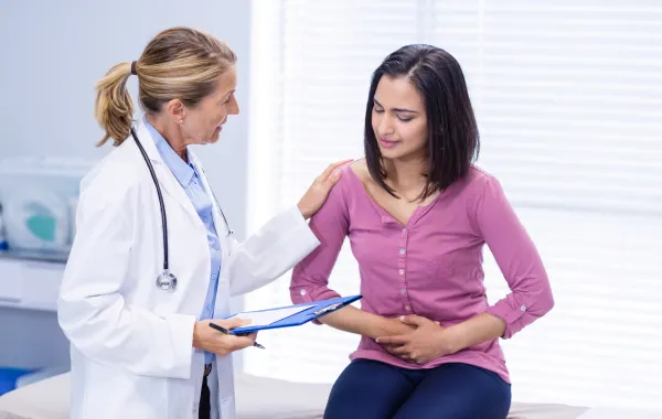 Foto de mujer con dolor en el estómago acompañada de una doctora