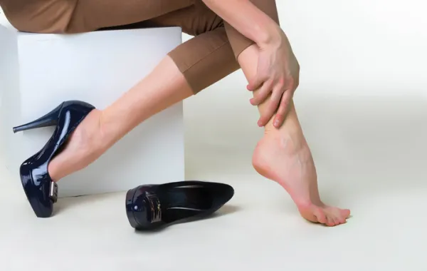 Foto de unos pies de mujer con el zapato quitado y que aprieta el piel con un mano