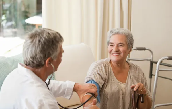 Foto de una mujer mayor atendida por un médico que le mide la tensión