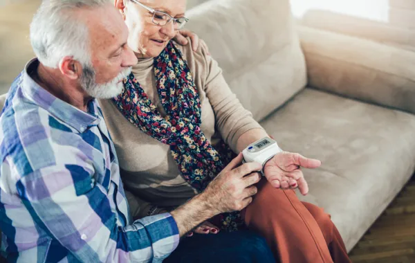 Foto de un pareja de personas mayores mirando un dispositivo que tienen en la muñeca