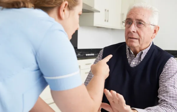Foto de enfermera señalando con un dedo a un anciano con cara seria