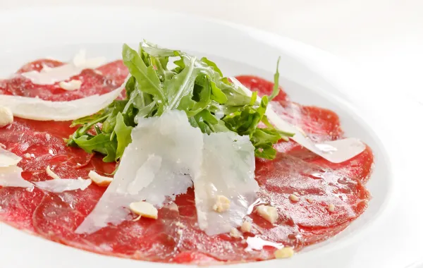 Un plato con jamón serrano, queso y rúcula